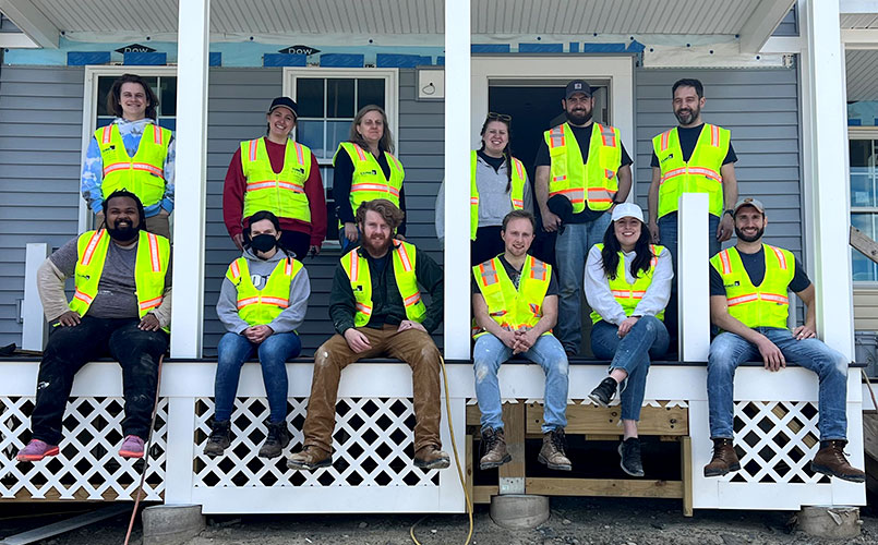 Group photo of the 12 CUBE 3 volunteers on the porch of the house